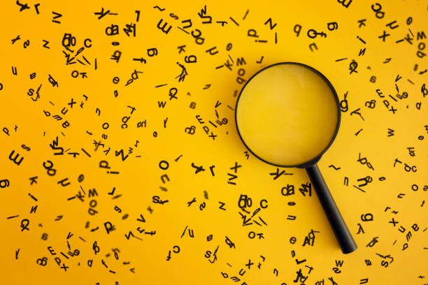 magnifying with wooden alphabets around on yellow background